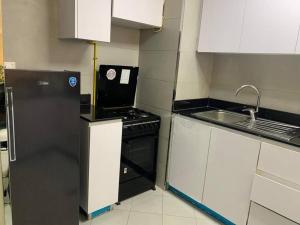 La cuisine est équipée d'un réfrigérateur noir et d'un évier. dans l'établissement A Calm&Cozy 1BR-20 MIN-DXB AIRPT, à Dubaï