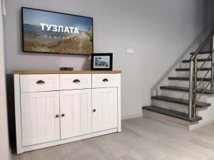 a living room with a tv on a wall and a staircase at Тузлата пентхаус / Tuzlata penthouse in Balchik