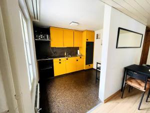 una cucina con armadi gialli e tavolo di Newly furnished beautiful old building apartment in the center with Apple TV a St. Gallen