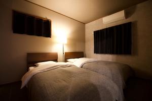 宮古島にあるVILLA CORALLIUM -MIYAKO-の小さな部屋(照明付)内のベッド2台