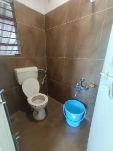 a bathroom with a toilet and a blue bucket at Osaree Agro and Art Hub in Kolhapur