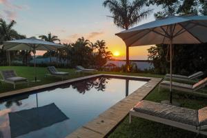 una piscina con sombrillas y sillas y una puesta de sol en Essenwood House en Durban