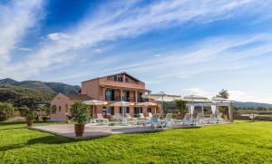 ein Haus mit einer Liegewiese und Stühlen davor in der Unterkunft Eleni Luxury Villa in Almiros Beach