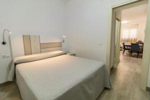 a bedroom with a white bed and a dining room at SAN ANDRÉS 13 in Torre del Mar
