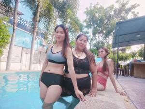 three women are sitting next to a swimming pool at Chic Chill Party Hua-Hin Private Poolvilla from beach 3km in Hua Hin