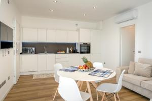 uma cozinha e sala de estar com uma mesa branca e cadeiras em Ferrari Apartments Ponente em Caorle