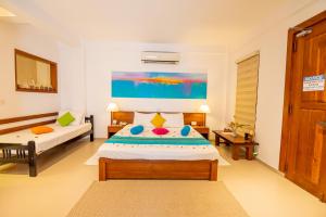 a bedroom with two beds and a painting on the wall at The Residence Hikkaduwa in Hikkaduwa