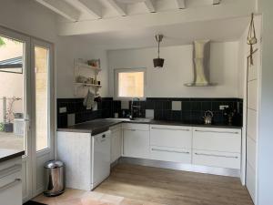 a kitchen with white cabinets and black tiles on the walls at Bâtisse en pierre XVII siècle 115 M² avec terrasse in Ambarès-et-Lagrave