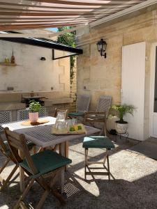 een patio met een tafel en stoelen en een grill bij Bâtisse en pierre XVII siècle 115 M² avec terrasse in Ambarès-et-Lagrave
