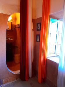 a room with an orange curtain and a mirror at Les Jardins du M'goun in El Kelaa des Mgouna