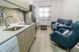 a kitchen with a sink and blue chairs in a room at SAN ANDRÉS 13 in Torre del Mar