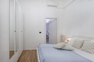 a white bedroom with a bed and a mirror at Natty Family Apartment in Carignano by Wonderful Italy in Genova
