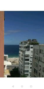 een groot wit gebouw met de oceaan op de achtergrond bij Designer Apartment Leme in Rio de Janeiro