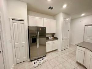 uma cozinha com um frigorífico de aço inoxidável e armários brancos em Grand Family Deluxe 4BR House near Disney Parks em Davenport