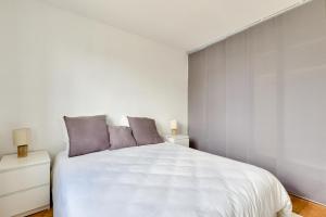 a bedroom with a large white bed with purple pillows at New ! Cosy Apt, ideal couple centre de Boulogne in Boulogne-Billancourt