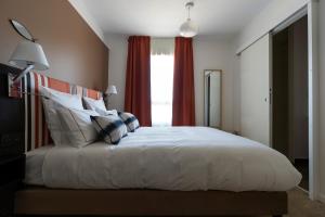 a bedroom with a large white bed with red curtains at HOTEL LE 25 in Andernos-les-Bains