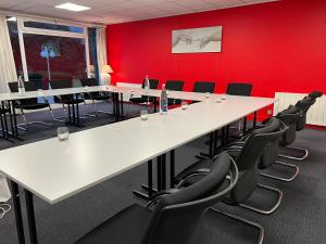 une salle de conférence avec des tables et des chaises blanches dans l'établissement Le Pré Saint Germain, à Louviers