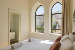 a bedroom with a white bed with two windows at The Pearl of Nachlaot Apartments in Jerusalem