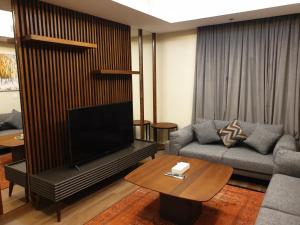 a living room with a couch and a flat screen tv at Terminal Inn Fully Furnished Hotel & Apartment- Al Mansoura in Doha