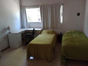 1 dormitorio con 2 camas, escritorio y ventana en Rincón de la selva en La Calera