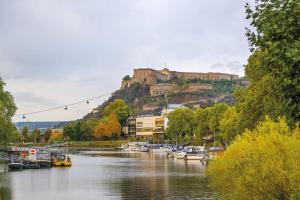 einen Fluss mit Booten und ein Schloss auf einem Hügel in der Unterkunft Diehls Hotel in Koblenz