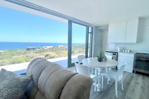 a living room with a couch and a table and a kitchen at Exclusive luxury & lifestyle suite in Mossel Bay
