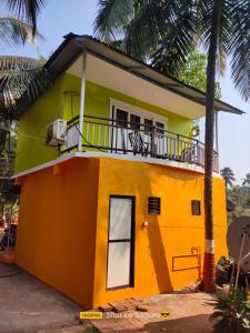 Casa pequeña de color amarillo y naranja con balcón en Casa Seaesta Beach Cottages and Suites, en Arambol