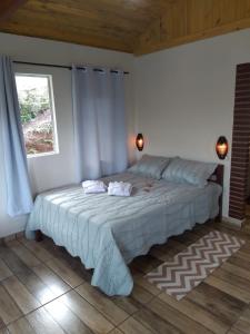 a bedroom with a large bed with a window at Chalé Som do Riacho com Hidromassagem e Lareira á 20 minutos de Gonçalves mg in Gonçalves