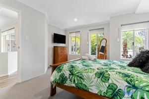 a bedroom with a bed with a green and white comforter at Halls Head Haven in Mandurah