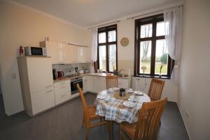 una cucina con tavolo e sedie e una cucina con armadietti bianchi di Herrenhaus Hohewarte a Lubecca