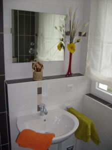 a bathroom with a sink and a vase with flowers at Apartment zum Dünenblick in Trassenheide