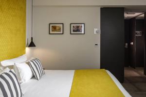 a bedroom with a bed with yellow and white pillows at Urban Rooms by NEU Collective in Il-Gżira