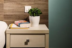 a table with a potted plant and books on it at 115 The Strand Hotel by NEU Collective in Il-Gżira