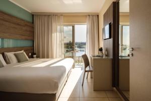 a hotel room with a bed and a desk and window at 115 The Strand Hotel by NEU Collective in Il-Gżira
