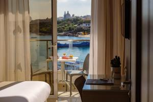 a hotel room with a bed and a view of the water at 115 The Strand Hotel by NEU Collective in Il-Gżira