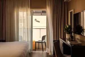 a hotel room with a bed and a chair and a window at 115 The Strand Hotel by NEU Collective in Il-Gżira