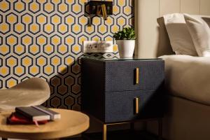 a bedroom with a dresser and a bed and a table at 115 The Strand Hotel by NEU Collective in Il-Gżira