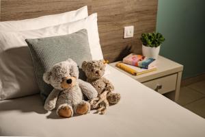 two teddy bears sitting on top of a bed at 115 The Strand Hotel by NEU Collective in Il-Gżira