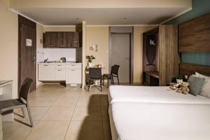 a bedroom with a large white bed and a kitchen at 115 The Strand Hotel by NEU Collective in Il-Gżira