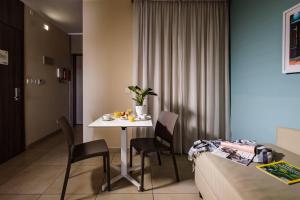 a room with a table and chairs next to a bed at 115 The Strand Hotel by NEU Collective in Il-Gżira