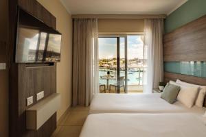 a hotel room with a bed and a balcony at 115 The Strand Hotel by NEU Collective in Il-Gżira