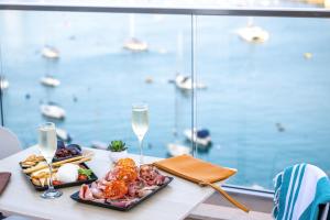 a table with a plate of food and glasses of wine at 115 The Strand Hotel by NEU Collective in Il-Gżira