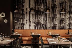 a restaurant with tables and chairs and a wall mural at 115 The Strand Hotel by NEU Collective in Il-Gżira