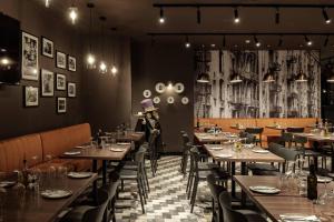 a restaurant with wooden tables and chairs and a woman sitting at a table at 115 The Strand Hotel by NEU Collective in Il-Gżira