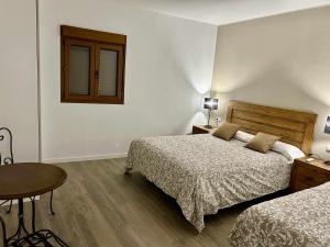 a bedroom with two beds and a table and a window at Casa Rural Namasté con SPA in Lleida