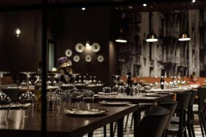 a dining room with tables and chairs with wine glasses at 115 The Strand Hotel by NEU Collective in Il-Gżira