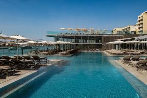a swimming pool with chairs and umbrellas on a building at 115 The Strand Hotel by NEU Collective in Il-Gżira