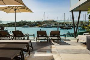 a patio with chairs and tables and a marina at 115 The Strand Hotel by NEU Collective in Il-Gżira
