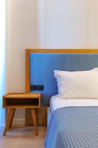 a bed with a blue headboard and a wooden night stand at Hotel Nertili in Sarandë +105 photos