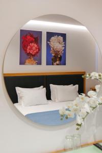 a mirror reflecting a bedroom with a bed with flowers at Hotel Nertili in Sarandë
